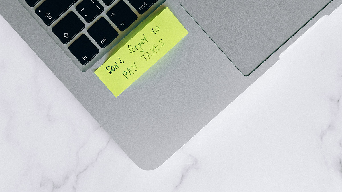 A sticker on a laptop says 'Don't forget to PAY TAXES'